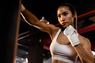 Asyalı kadın Muya Thai boksör eğitimi, spor salonunda kum torbasına yumruk atma. Sağlıklı spor ve spor yaşam tarzı, boks maçı için güç ve dayanıklılık eğitimi. Impetus