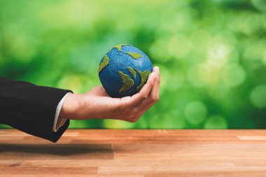 İşadamı temiz enerji ve sıfır CO2 emisyonu kullanarak sürdürülebilir dünya için çevresel farkındalığın sembolü olarak kağıt toprağı elinde tutuyor. Dünya 'yı kurtarmak için yeşil politikası olan çevre dostu bir şirket. Değiştir
