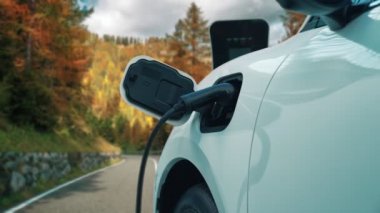 Tepe yolundaki şarj istasyonunda elektrikli arabanın çevresel farkındalığı için yenilikçi bir kavram. EV araba temiz çevre için yenilenebilir enerjiden güç alıyor.