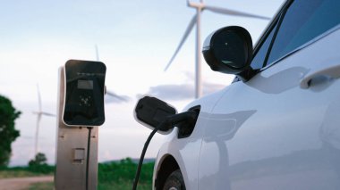 Çevreyi korumak için rüzgar türbininden yeşil ve yenilenebilir enerjiyle çalışan şarj istasyonunda şarj edilen gelişmiş gelecek enerji altyapısı konsepti.