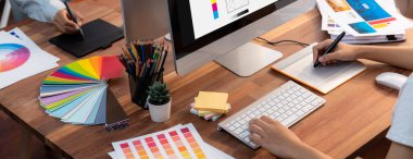 Grafik tasarımcısı, modern dijital stüdyo işyerinde profesyonel grafik ekibiyle benzersiz bir tasarım yaparken bilgisayar dizüstü bilgisayar ve grafik çizim kalemi üzerinde çalışır. Panorama çekimi. İnceleyin