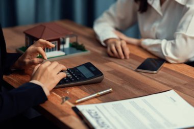 Temsilciyle ev kredisi sözleşmesini gözden geçiriyorum. Mali belgeleri ve vergi oranlarını, mülkiyet sahibi olmak için hesap makinesiyle analiz ediyorum. Yeni ev alımı ve finansman için anahtar imza. Coşkulu.