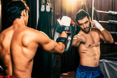 Asyalı ve Kafkasyalı Muay Thai boksörü boks antrenmanında boks antrenmanında boks antrenörüne yumruk atma, Muay Thai boks tekniği ve becerilerini sergileme. Impetus