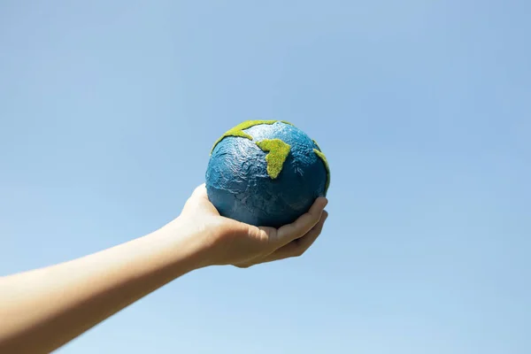 stock image Young boys hand holding planet Earth globe with sky and cloudscape background as Earth day to save this planet with ESG principle and environment friendly energy for brighter future. Gyre