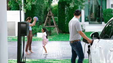 İlerici ebeveynler kızlarını okuldan alırken elektrikli araba ve yenilenebilir enerji kavramını kullandılar, evdeki EV otomobil için şarj istasyonu. Alternatif eko taşımacılığı.