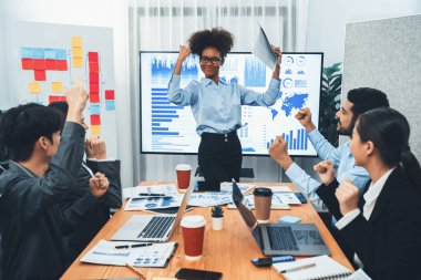 İş adamları TV ekranında başarılı bir sunum veya veri analizi toplantısından sonra kutlama yapıyorlar. Mutlu takım ofis odasında toplanıyor, kutlama jestleriyle işbirliği için tezahürat yapıyorlar. Uyum