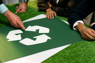 Geri dönüşüm simgesi, geri dönüşüm temiz ekosistem için yeniden kullanım kavramını azaltırken, atık yönetimi üzerine eko iş yatırımları planlayan işadamlarıyla birlikte ofiste bir toplantı masasında. Antika