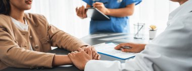 Doktor, doktor kliniğinde destekleyici ve profesyonel olduğu için genç hasta elini tutarken tıbbi teşhis raporunu ve şefkatli bir sağlık hizmeti danışmanlığı sunduğunu göster. Neoterik