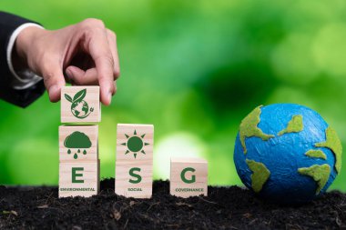 ESG sembolü ahşap küplü kağıt gezegen tutan bir iş adamı. Çevresel, sosyal ve yönetimsel dünyayı kurtarmak için sürdürülebilir şirket gelişimi. Değiştir