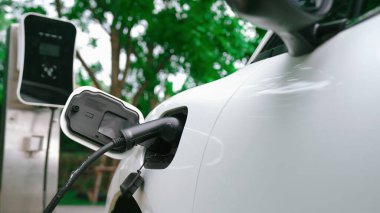 Yakın çekim yenilikçi modern ulaşım konsepti, elektrikli araba şarj istasyonunda gökyüzünden yansıyan yüksek detay ile şarj ediliyor. Yenilenebilir enerji tarafından kullanılan çevre dostu elektrikli araç.