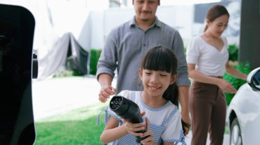 Elektrikli araç şarj istasyonu olan, sağlıklı ve temiz bir çevreyi teşvik eden yenilikçi bir aile kavramı. Sürdürülebilir, temiz enerji teknolojisiyle çalışan elektrikli araç..