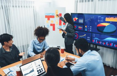 Genç Asyalı iş kadını modern toplantıda TV ekranında veri analizi paneli sunuyor. Bir grup iş adamıyla konferans odasında iş sunumu. Uyum