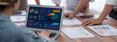 Panorama analist ekibi, FBI Fintech 'i kullanarak dizüstü bilgisayarla mali raporu analiz ediyor. İş adamları iş görüşü için dizüstü bilgisayarda gösterilen kontrol panelini inceliyor. İnceleyin