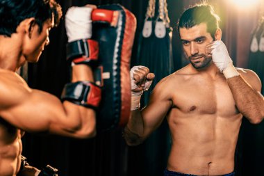 Asyalı ve Kafkasyalı Muay Thai boksörü boks antrenmanında boks antrenmanında boks antrenörüne yumruk atma, Muay Thai boks tekniği ve becerilerini sergileme. Impetus