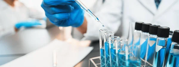 専門科学者のグループは 医療研究室で化学実験を行い ピペットからの液体の正確な量を慎重にワクチン薬や抗生物質の開発のための試験管にドロップします — ストック写真