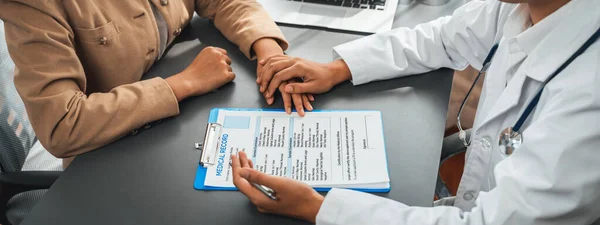 医師は医療診断報告書を提示し 若い患者の手を握りながら思いやりのある医療相談を提供します — ストック写真