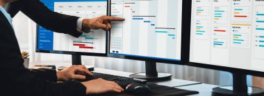 Projeyi koordine eden ve güncelleyen proje ekibi Gantt çizelge yazılımını kullanarak bilgisayarda program planladılar. Şirket işi için zaman ve süre belirleyen iş adamları. Önde.