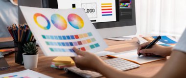Grafik tasarımcısı, modern dijital stüdyo işyerinde profesyonel grafik ekibiyle benzersiz bir tasarım yaparken bilgisayar dizüstü bilgisayar ve grafik çizim kalemi üzerinde çalışır. Panorama çekimi. İnceleyin