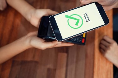 QR kodu parasız ödeme taraması için ekranda gösterilir. Kapalı eller, mobil uygulamadan elektronik işlem yoluyla para aktarmak için akıllı telefonu tutuyor. Hızlı ödeme için barkod teknolojisi. Coşkulu.