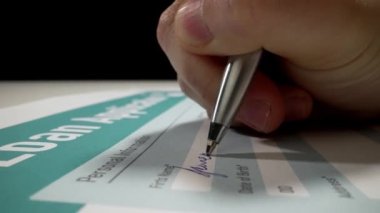 El yapımı kredi başvuru formunu kişisel veri ve imzayla dolduran makro çekim hareketi. Kredi, ipotek veya öğrenci kredisi başvurusu.