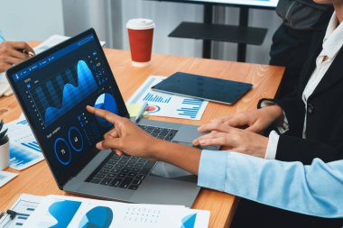 Çok ırklı analist ekibi toplantı masasındaki finansal verileri analiz etmek için BI Fintech yazılımı kullanıyor. Finansal konsol veri ekranında pazarlama göstergesi için analiz edilmiş grafikle birlikte. Uyum