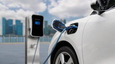 Elektrikli araba şarj istasyonuna bağlandı. Şehrin arka planına sahip EV şarj kablosu ile pili şarj etmek için. Geleceğin yenilikçi her arabası ve enerji sürdürülebilirliği. İnceleyin