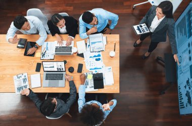 Modern toplantı odasındaki TV ekranında veri analizi paneliyle üst görünüm iş sunumu. İş adamlarının iş pazarlama stratejisini planlamak için beyin fırtınası yapması ya da birlikte çalışması. Uyum