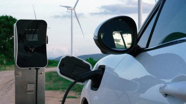 Çevreyi korumak için rüzgar türbininden yeşil ve yenilenebilir enerjiyle çalışan şarj istasyonunda şarj edilen gelişmiş gelecek enerji altyapısı konsepti.