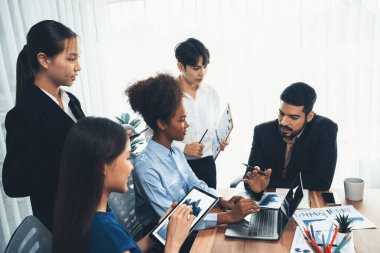 Çok ırklı analist ekibi toplantı masasındaki finansal verileri analiz etmek için BI Fintech yazılımı kullanıyor. Finansal konsol veri ekranında pazarlama göstergesi için analiz edilmiş grafikle birlikte. Uyum