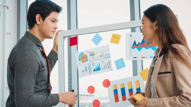 İş adamları ofisteki proje planlama kurulunda çalışıyor ve proje gelişimini analiz etmek için iş arkadaşlarıyla sohbet ediyorlar. Düzenli olması için cama yapıştırılmış yapışkan notlar kullanıyorlar. Jivy