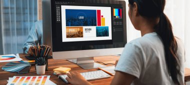 Grafik tasarımcısı, modern dijital stüdyo işyerinde profesyonel grafik ekibiyle benzersiz bir tasarım yaparken bilgisayar dizüstü bilgisayar ve grafik çizim kalemi üzerinde çalışır. Panorama çekimi. İnceleyin