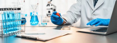 Bilimadamları tıbbi laboratuvarda kimyasal deneyler yapıyor. Aşı ilacı veya antibiyotik gelişimi için pipetten deney tüpüne kesin miktarda sıvı bırakıyor. Neoterik