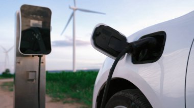 Çevreyi korumak için rüzgar türbininden yeşil ve yenilenebilir enerjiyle çalışan şarj istasyonunda şarj edilen gelişmiş gelecek enerji altyapısı konsepti.