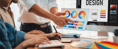 Grafik tasarımcısı, modern dijital stüdyo işyerinde profesyonel grafik ekibiyle benzersiz bir tasarım yaparken bilgisayar dizüstü bilgisayar ve grafik çizim kalemi üzerinde çalışır. Panorama çekimi. İnceleyin