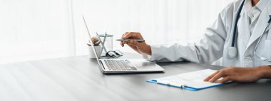 Doktor, tibbi raporu laptopla dikkatlice gözden geçir ve hastaların doktor muayenehanesinde etkili bir sağlık tedavi planı için hastalık teşhisi koy. Profesyonel tıbbi değerlendirme. Neoterik