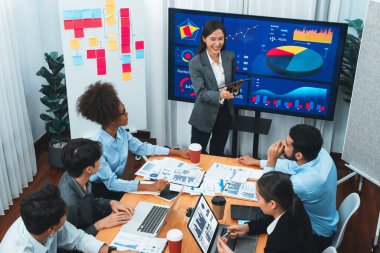 Modern toplantı odasındaki TV ekranında veri analizi paneliyle üst görünüm iş sunumu. İş adamlarının iş pazarlama stratejisini planlamak için beyin fırtınası yapması ya da birlikte çalışması. Uyum