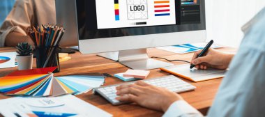 Grafik tasarımcısı, modern dijital stüdyo işyerinde profesyonel grafik ekibiyle benzersiz bir tasarım yaparken bilgisayar dizüstü bilgisayar ve grafik çizim kalemi üzerinde çalışır. Panorama çekimi. İnceleyin