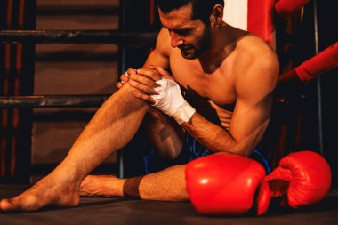 Şiddetli boks antrenmanı ve dövüş müsabakasından sonra acı ve sakatlığı olan beyaz bir boksör ringin kenarında oturuyor. Spor konseptinde fiziksel yaralanma. Impetus