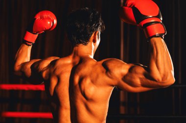 Muzaffer Muay Thai boksörü zaferle poz veriyor, güçlükle kazandığı zaferinin tadını çıkarıyor ve güçlü ve kaslı vücudunu gururla sergiliyor. Impetus