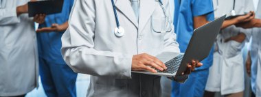 Hastanede dizüstü bilgisayar ve tabletle birlikte çalışan doktor hemşire ve sağlık uzmanlarına sahip tıbbi personel ekibi. Panoramik pankartta tıbbi işyeri ve sağlık hizmetleri topluluğu. Neoterik