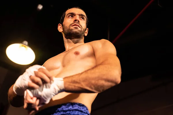 stock image Caucasian boxer portrait with muscular and athletic body wrapping his hand or fist on the ring be fore the boxing fight match or training. Impetus