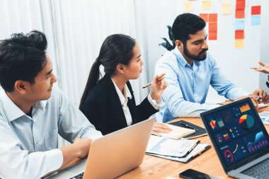 Çok ırklı analist ekibi toplantı masasındaki finansal verileri analiz etmek için BI Fintech yazılımı kullanıyor. Finansal konsol veri ekranında pazarlama göstergesi için analiz edilmiş grafikle birlikte. Uyum