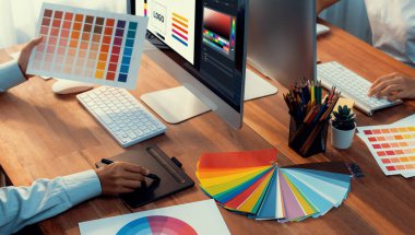 Grafik tasarımcısı, modern dijital stüdyo işyerinde profesyonel grafik ekibiyle benzersiz bir tasarım yaparken bilgisayar dizüstü bilgisayar ve grafik çizim kalemi üzerinde çalışır. Panorama çekimi. İnceleyin