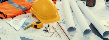 Mimari mimari tasarım, güvenlik kaskı veya başlığı takılı mühendislik çalışma alanı masası üzerine müteahhit proje belgeleriyle tasarım için tasarım planı ve mühendislik aracı tasarladı. İçgörü