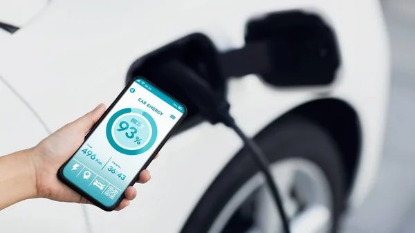 スマートフォンはスマートEvモバイルアプリケーションのバッテリーステータスを表示し Ev車はガレージ内の家庭用充電ステーションで電気を充電します 将来の革新的なEv車とエネルギー持続可能性 Peruse — ストック写真
