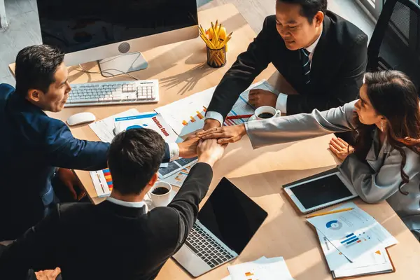 Happy business people celebrate teamwork success together with joy at office table shot from top view . Young businessman and businesswoman workers express cheerful victory show unity support . Jivy