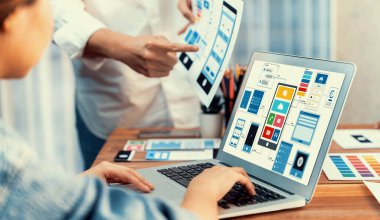 Dizüstü bilgisayar ekranında mobil uygulama için UI ve UX tasarımları tasarlayan ön uç geliştirici ekibin panorama görüntüsü. Kullanıcı dostu UI tasarımı için kullanıcı arayüzü geliştirme ekibi planlama. İnceleyin