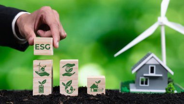 İş adamı ESG sembol küpünü ev ve rüzgar türbini modeline koydu. Çevresel çevre bilincine sahip etik şirket tarafından gelecekte orman yenilenmesi kavramı. Değiştir
