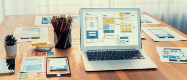 Dizüstü bilgisayar ekranında web ya da mobil uygulama UI UX için dijital ve kağıt kablo tasarımları. Beyin fırtınası ve tasarım uygulama çerçevesi için geliştirici çalışma alanının panoramik görüntüsü. İnceleyin