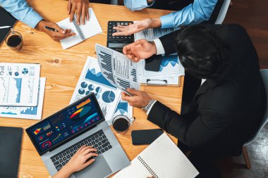Üst düzey iş analist grubu toplantı masasındaki finansal veri raporunu analiz ediyor. İş zekası analizine göre çizelge ve grafik paneli. Çok titiz.